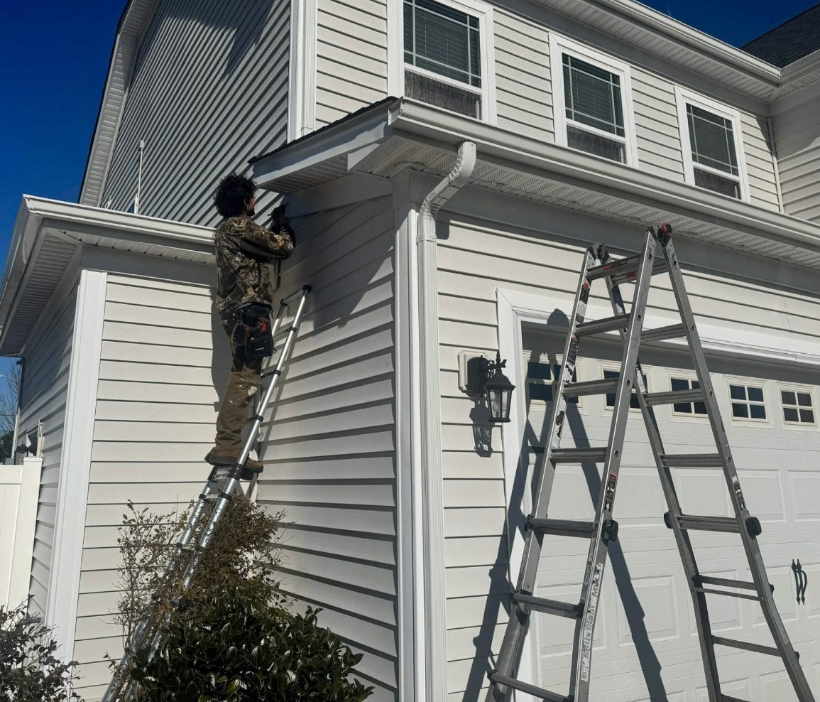 Kyle hand-cleaning a gutter on a roof