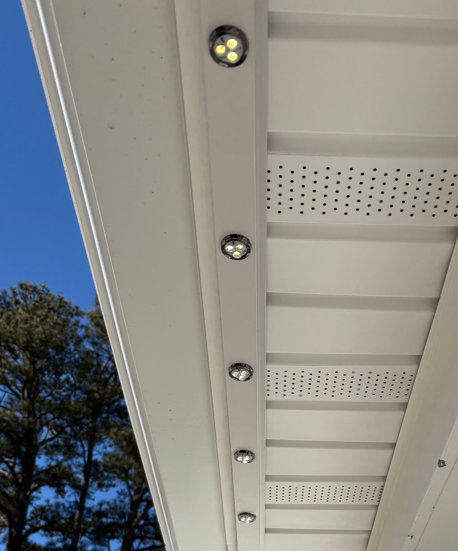 Close-up of the aluminum track and recessed RGB LED bulbs installed under a home's soffit